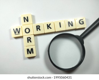 Selective focus.Toys letters with text NORM WORKING and magnifying glass on white background.