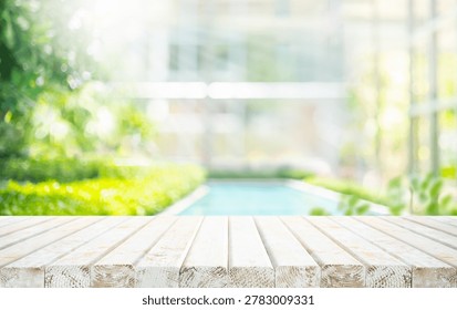 Selective focus.Wood table top on garden with swimming pool background.