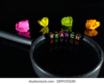Selective focus.Word SEARCH from a black dice on a magnifying glass with crumpled paper color and  black background.Shot were noise and film grain.