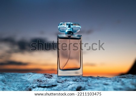 Selective and luxurious perfumes. Close up of glass transparent perfume bottle on the background of a twilight sunset. Presentation of evening toilet water.