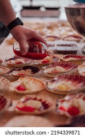 A Selective Shot Of A Man's Hand Pouring Sauce On A Raw Scallop