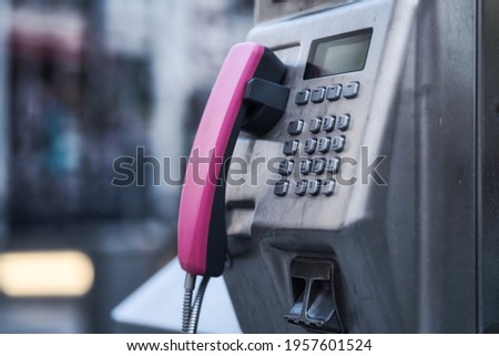 A selective shot of a pink payphone in city street
