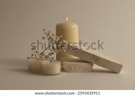 Selective soft focus Burning blur candles with flower, stones podium. Evening night Light and shadow gray neutral background. Minimalist still life.