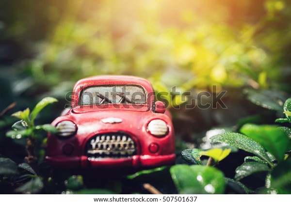 Selective Soft Focus\
-  Dark Tone Vintage Red Classic Car Parking on Leaves Floor with\
Sunlight Flare\
Background
