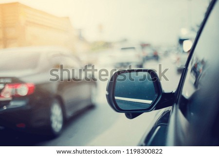 Selective and soft focus of side mirror and blurry car on road with traffic jam.