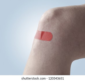 Self Adhesive Read Colour Band Aid On Knee. On Blue Background.