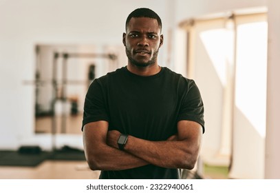 Self assured adult black male coach in t shirt with smart watch crossing hands while standing in gym against blurred background - Powered by Shutterstock