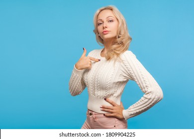 Self confident arrogant woman with curly blond hair pointing finger on herself, bragging with achievements, egoism. Indoor studio shot isolated on blue background - Shutterstock ID 1809904225