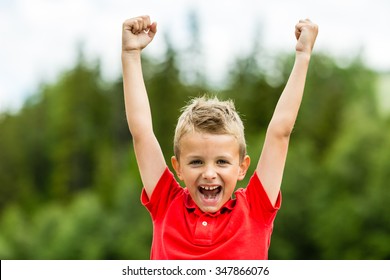 Self confident boy with raised fists celebrating a recent success or victory.