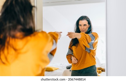 
Self confident single woman pointing finger at her reflection in mirror, dancing and felling good. Independent person with high self esteem talks positive and I can do it motivation.  - Shutterstock ID 2067448814
