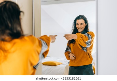 
Self confident single woman pointing finger at reflection in mirror dancing and felling good. Independent person with high self esteem talk positive I can do it motivation.