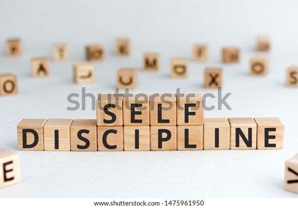 Self\
discipline - words from wooden blocks with letters, self-discipline\
concept, random letters around, white \
background