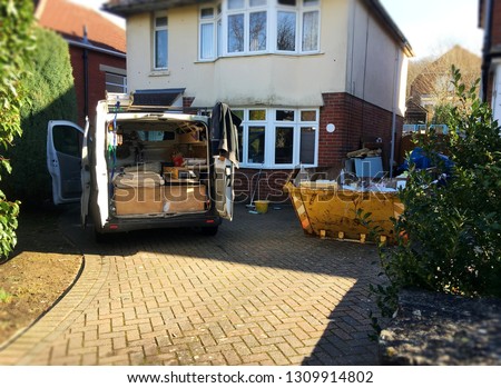 Self employed builder van with building tools & yellow skip full of rubbish situated near the house. Photo for background use as home renovation, investment project. Space to add text on driveway.