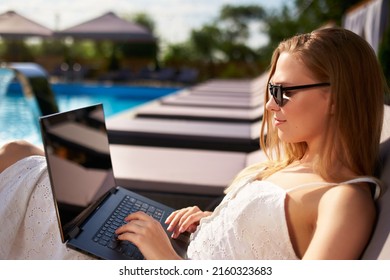 Self employed woman telecommuting with team on project from tropical island resort. Freelancer businesswoman doing remote work with laptop on swimming pool beach bed at spa. Girl tanning and relaxing. - Powered by Shutterstock