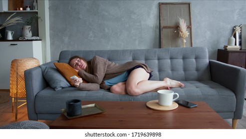 Self isolation and depression. Young beautiful Caucasian woman lying down on sofa tired of watching TV at home alone.