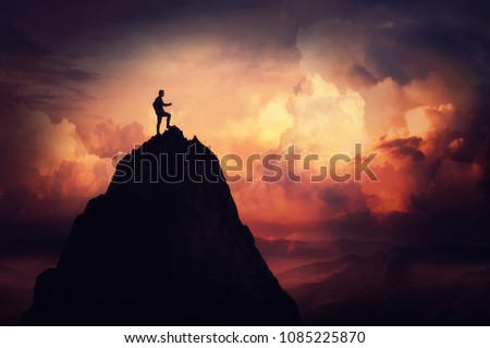 Self overcome concept as a businessman climbing a tall mountain over the clouds. Road to win and succes over sunset background. Achieving goals symbol.