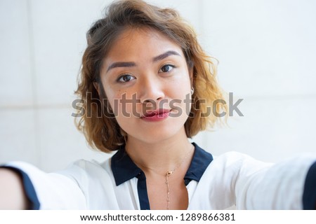 Self portrait of beautiful Chinese girl walking outdoors. Closeup of young attractive woman looking at camera. Selfie concept