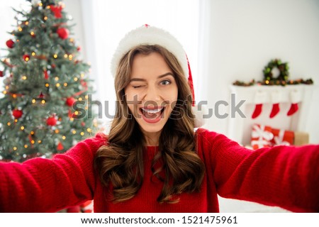 Self portrait of beautiful cute pretty sweet fooling girlfriend taking selfie in front of light of christmas tree wearing red cap