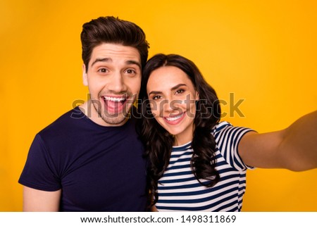 Self portrait of charming beautiful nice couple of spouses smiling at camera showing their teeth while isolated with yellow background