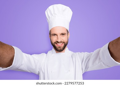 Self portrait of cheerful attractive chef cook in beret and white outfit with stubble shooting selfie on front camera of smart phone with two hands, isolated on grey background - Shutterstock ID 2279577253