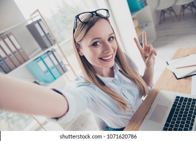 Self Portrait Of Cheerful, Positive, Attractive, Charming, Stylish Woman With Glasses On Head, Shooting Selfie On Front Camera, Having Leisure, Rest, Pause, Gesture V-sign, Sitting In Work Place