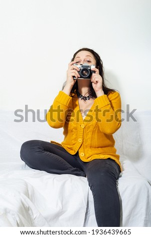 Self portrait of A girl  in buckwheat color knitted sweater photographs with Vintage camera in her hands