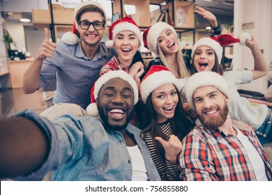 Self portrait of mixed race unity of african, american, asian, caucasian friends, happy bearded men and beautiful women in red santa hat showing thumb up, like, ok gesture to the camera in office - Powered by Shutterstock