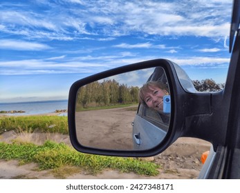 Self portrait at side view mirror of a car in travel, trip on nature