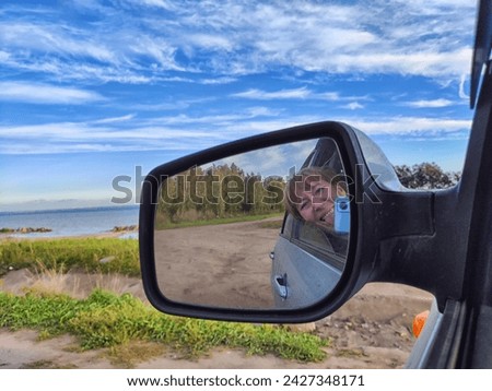 Self portrait at side view mirror of a car in travel, trip on nature