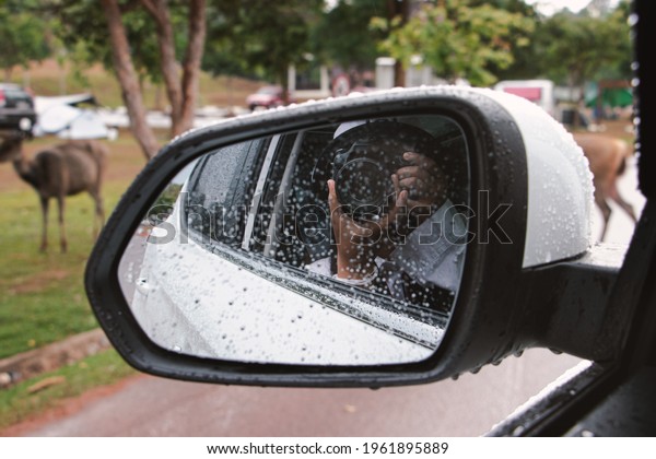 self\
portrait at side view mirror of  car in Rainy\
day.