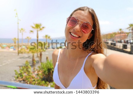Self portrait of a young beautiful woman with sunglasses on the beach