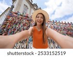 Self portrait of young tourist woman in front of the church of Our Lord of Bonfim full of colored ribbons in Salvador de Bahia, Brazil