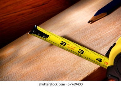 Self Retracting Construction Tape Measure And Carpenter Pencil On Wood Plank For A Custom Cabinetry Woodworking Project In A Carpentry Workshop