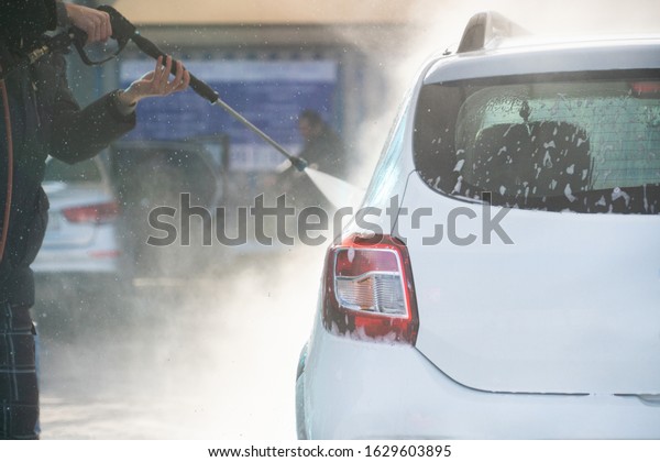 Self service high pressure car wash. Vehicle covered
with foam