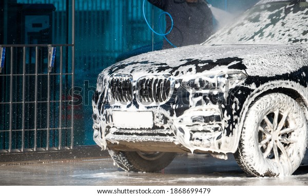 Self service high pressure car wash. Vehicle covered
with foam