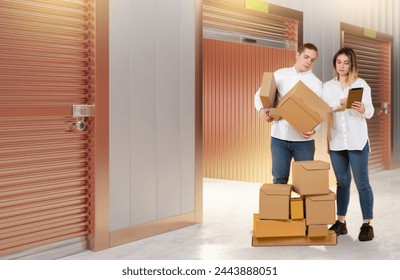 Self storage unit. Couple with boxes near safekeeping room. Self storage unit for storing things. Man and woman prepare boxes for storage. People inside warehouse for personal belongings