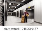 Self storage unit for men. Warehouse space rental. Self storage units inside building. Corridor with gates to separate warehouse rooms. Man picks up parcels from storage unit. Place for safekeeping
