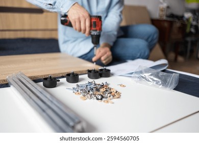 Self-assembly using a guide. House design. Close-up of a man's hands assembling a wooden bed using a hexagon to insert screws into the bed frame.Collection of wooden furniture. Husband for an hour.