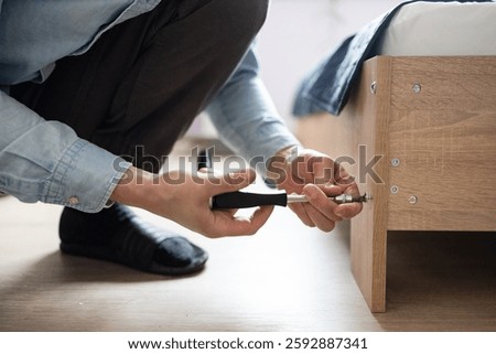 Self-assembly using a guide. House design. Close-up of a man's hands assembling a wooden bed using a hexagon to insert screws into the bed frame.Collection of wooden furniture. Husband for an hour.