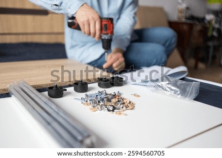 Self-assembly using a guide. House design. Close-up of a man's hands assembling a wooden bed using a hexagon to insert screws into the bed frame.Collection of wooden furniture. Husband for an hour.