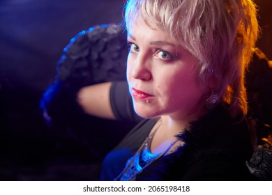 Self-assured Adult Blonde Middle Age Woman With Black Angel Wings. Model Posing In Studio On Black Background. Dangerous Cupid On Valentine's Day