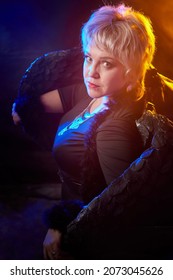 Self-assured Adult Blonde Middle Age Woman With Black Angel Wings. Model Posing In Studio On Black Background. Dangerous Cupid On Valentine's Day In Studio