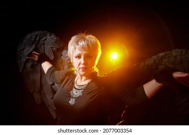 Self-assured Adult Blonde Middle Age Woman With Black Angel Wings. Model Posing In Studio On Black Background. Dangerous Cupid On Valentine's Day In Studio