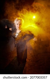 Self-assured Adult Blonde Middle Age Woman With Black Angel Wings. Model Posing In Studio On Black Background. Dangerous Cupid On Valentine's Day In Studio