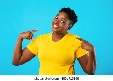 Self-Confidence. Happy Plus-Size Black Woman Pointing Fingers At Herself Posing Standing Over Blue Studio Background, Smiling To Camera. Choose Me, I'm The Best Concept