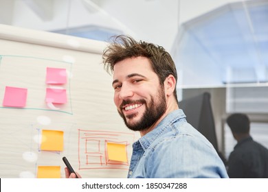 Self-confident founder in front of a flipchart with sticky notes and graphics