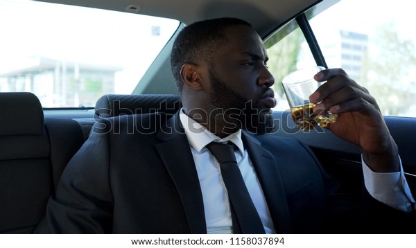 Self-confident rich man drinking alcohol in car,\
luxury lifestyle,\
success