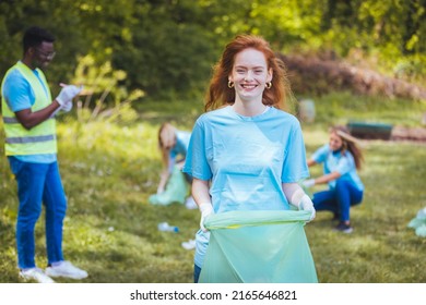 A self-confident young woman participates in a community cleansing action with her friends. Portrait of a young beautiful girl with a garbage bag