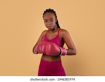 Self-Defence Classes. Portrait Of Young Sporty Black Woman Wearing Boxing Gloves, Confident African American Female Standing Over Beige Background In Studio, Ready To Attack, Copy Sace - Powered by Shutterstock