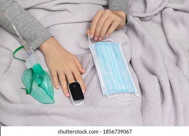 Self-diagnosis Of Oxygen Deficiency. Pulse Oximeter, Protective Mask And Inhaler In Woman Hands. Health Concept And Virus Protection Concept